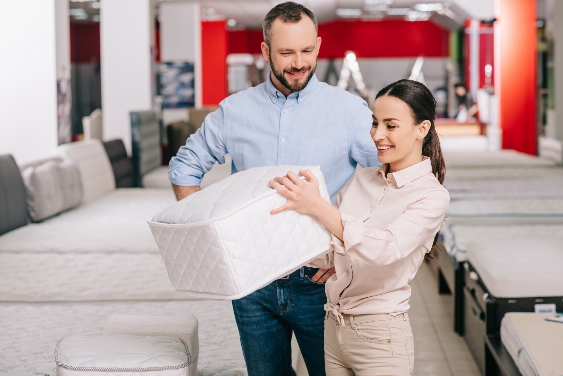 couple choosing folding mattress together in furniture store with arranged mattresses